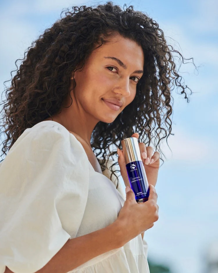 Copper Firming Mist de la marca Is Clinical: Mujer mostrando el producto para apreciar el tamaño